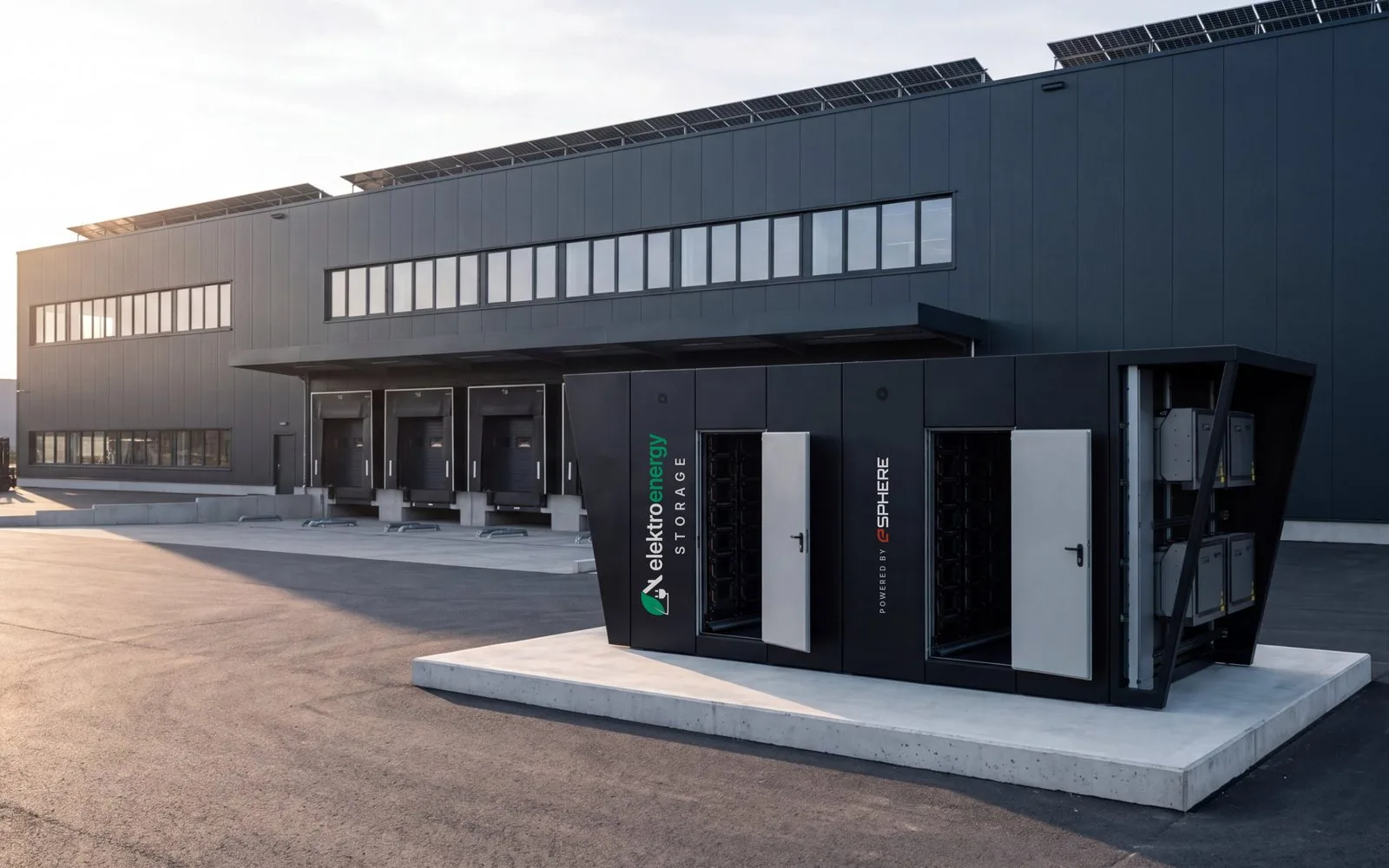 Großspeicher mit der Aufschrift elektroenergy STORAGE, powered by eSphere, neben einer Produktionshalle