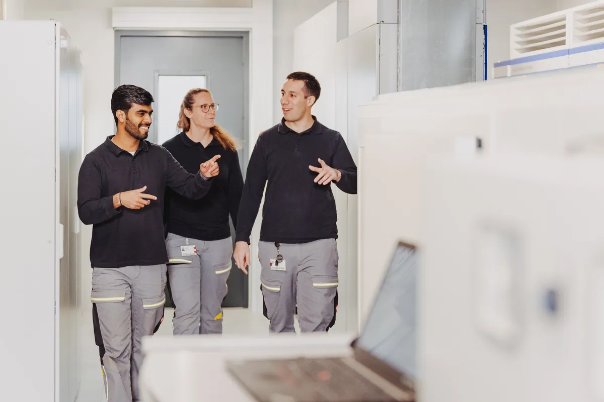 Drei Mitarbeitende von eSphere im Gespräch auf dem Weg durch das Testzentrum